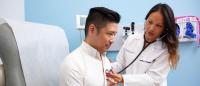 Female Nurse Practitioner checking heartbeat of patient sitting in chair